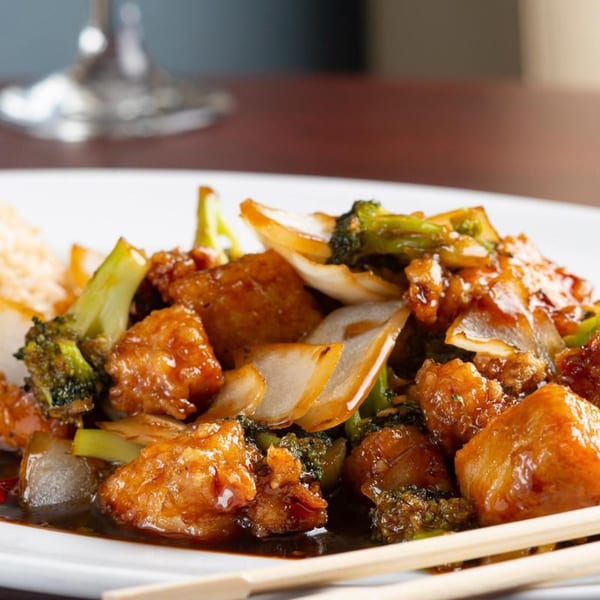 Sweet and sour chicken with broccoli and onions, served with rice and chopsticks at Tea Tree Asian Bistro.