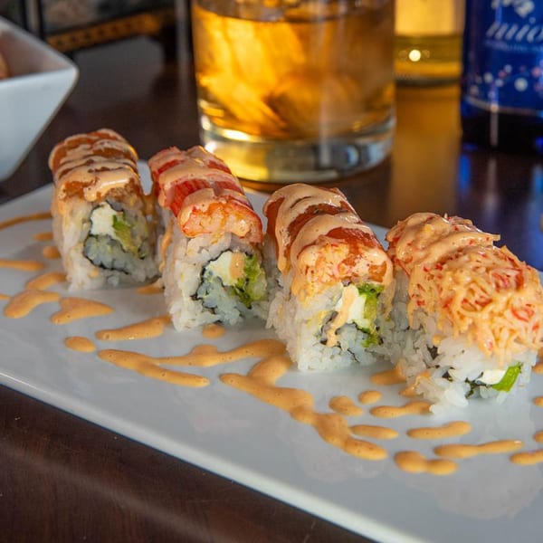 Four Tea Tree Asian Bistro sushi rolls with shrimp and sauce on a white plate.