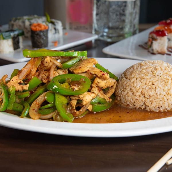 Tea Tree Asian Bistro's chicken and green pepper stir-fry with brown rice, and sushi in the background.