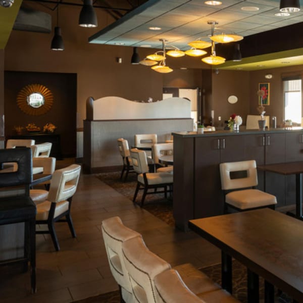 Interior of Tea Tree Asian Bistro with modern lighting, dark walls, and light-colored seating.