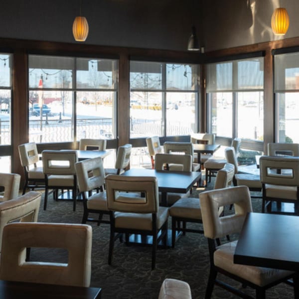 Interior of Tea Tree Asian Bistro, featuring empty dining tables and chairs by large windows.
