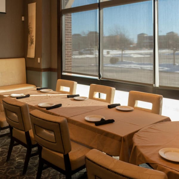 Dining room at Tea Tree Asian Bistro with set tables, chairs, and large windows overlooking a snowy landscape.