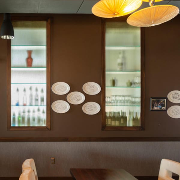 Brown wall with two illuminated display cases, decorative plates, and a framed picture.