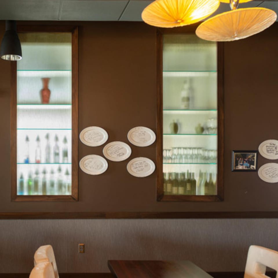 Brown wall with two illuminated display cases, decorative plates, and a framed picture.