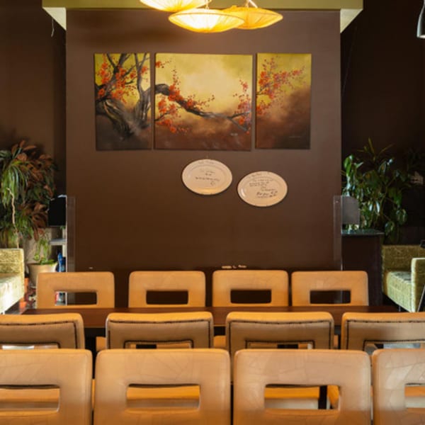 A dining room at Tea Tree Asian Bistro with a long table, chairs, and Asian-inspired artwork.